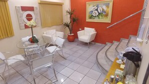 Habitación de hotel con comedor, planta en maceta, un cuadro y una escalera.