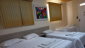 Habitación de hotel con dos camas, cabecero de madera, una obra de arte colorida en la pared y una puerta.