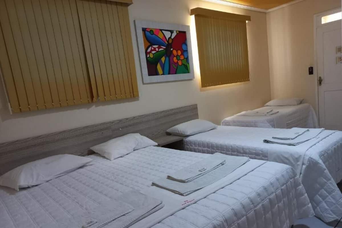 Une chambre d’hôtel avec deux lits, une tête de lit en bois, une œuvre d’art colorée accrochée au mur et une porte.