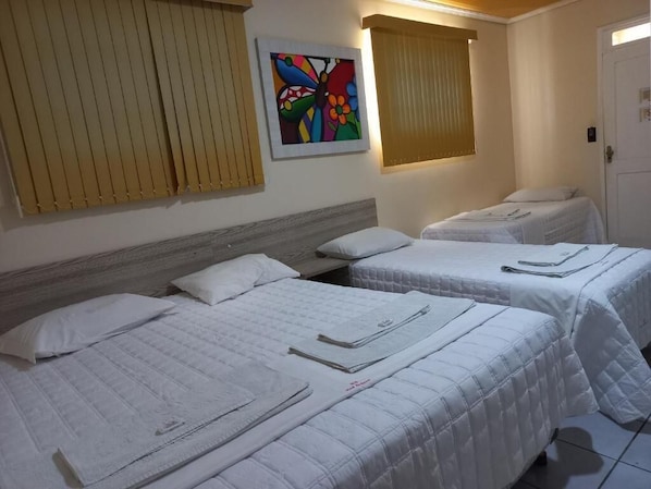 A hotel room with two beds, a wooden headboard, a colorful artwork on the wall, and a door.