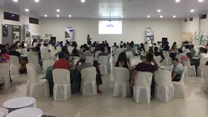 A conference room with rows of white-covered chairs facing a presentation screen. - Dallas Palace Hotel (Rio Paranaiba)