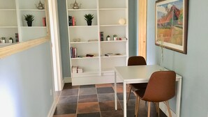 A room with a white desk, brown chair, and a white shelving unit with books and decorative items. - Ebogaard Bed and Breakfast (Hillerod)