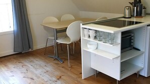 A compact kitchen with a dining area, featuring a white countertop, a kettle, and a coffee maker. - Ebogaard Bed and Breakfast (Hillerod)
