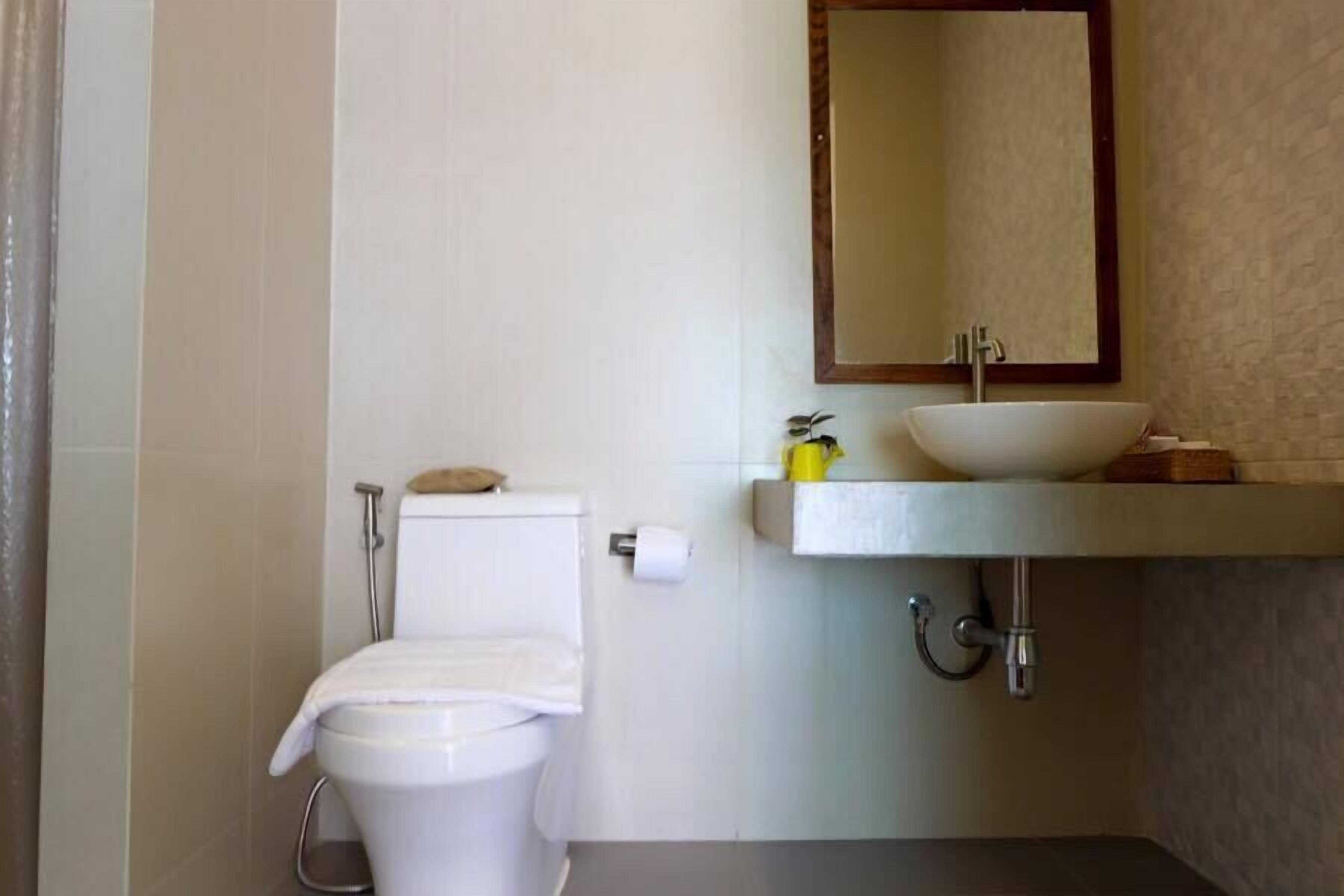 Et badeværelse med toilet, vask og spejl.