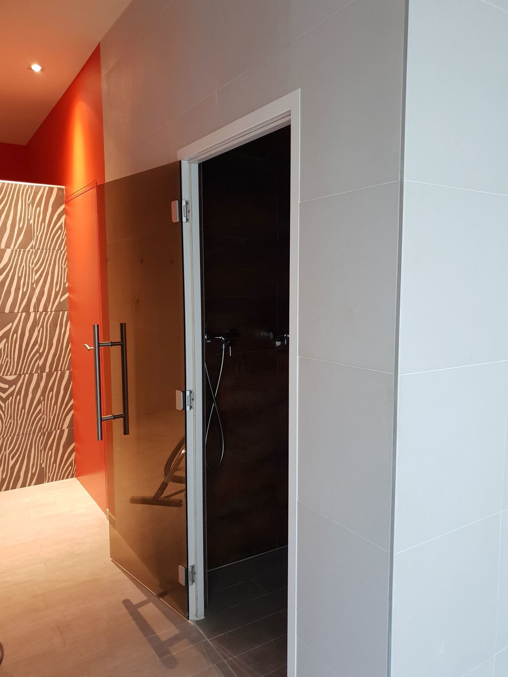 A modern bathroom with a shower, a zebra-patterned wall, and a white tiled floor.