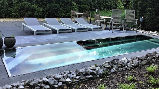 A modern outdoor pool area with lounge chairs and a dining set. - Zen Your Life (Dilbeek)