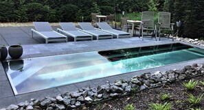 A modern outdoor pool area with lounge chairs and a dining set. - Zen Your Life (Dilbeek)