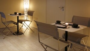 A compact dining area with a table set for two, foldable chairs, a floor lamp, and a door in the background. - Zen Your Life (Dilbeek)