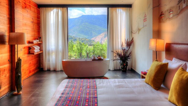 A hotel room with a large bed, a bathtub, and a view of mountains. - Dewa Thimphu by Realm (Thimphu)