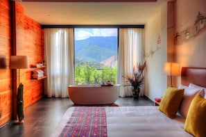 A hotel room with a large bed, a bathtub, and a view of mountains. - Dewa Thimphu by Realm (Thimphu)