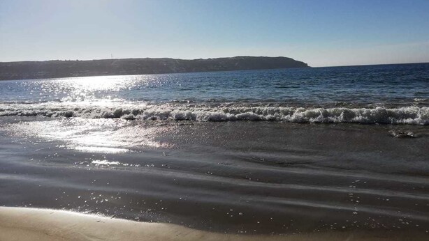 Ein Strand mit Wellen und blauem Himmel.