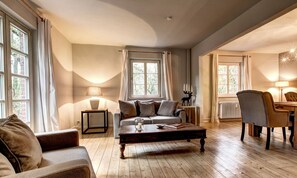 A cozy living room with a sofa, a coffee table, and a dining area with chairs and a table.