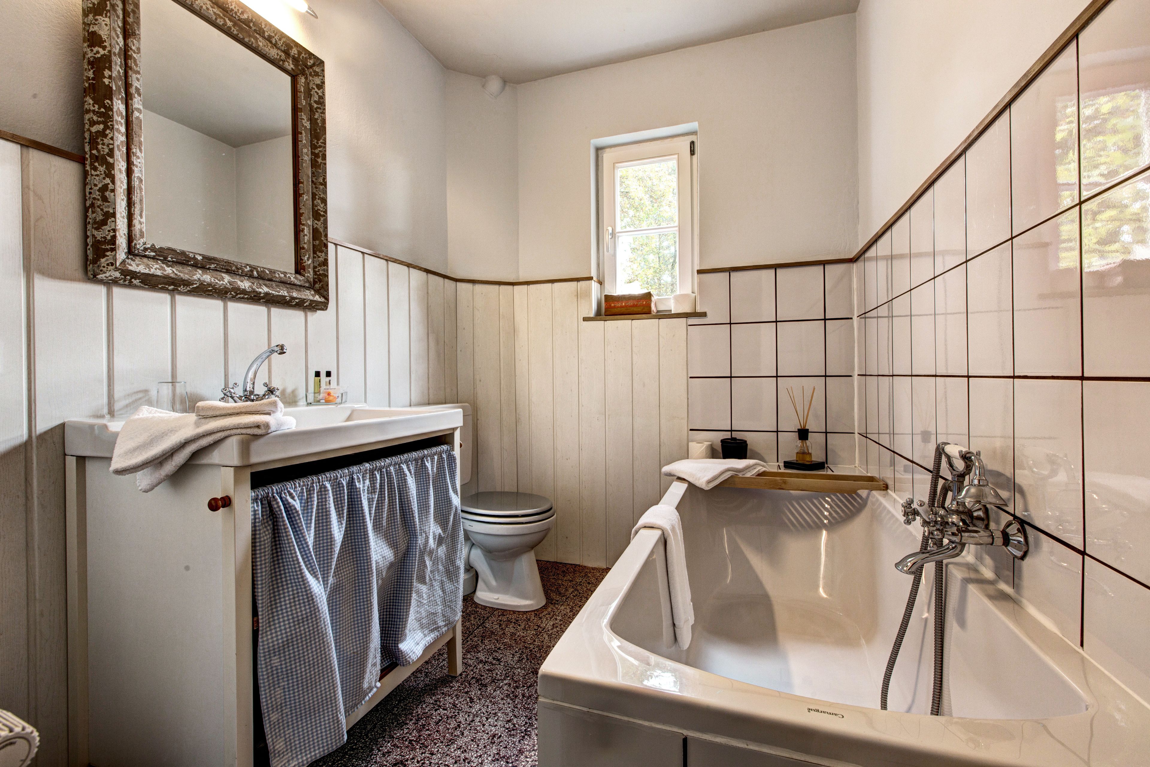 A bathroom with a bathtub, toilet, sink, and mirror.