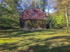 A house with a tiled roof, surrounded by a grassy yard and trees.
