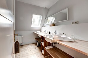 A modern bathroom with two sinks, a large mirror, and a window providing natural light.