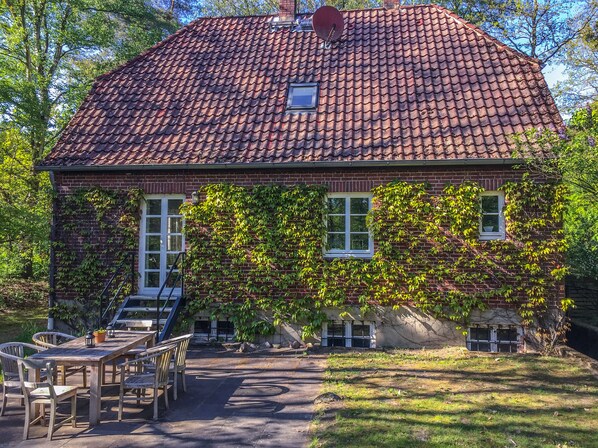 A house with a tiled roof, brick walls, and ivy-covered windows.