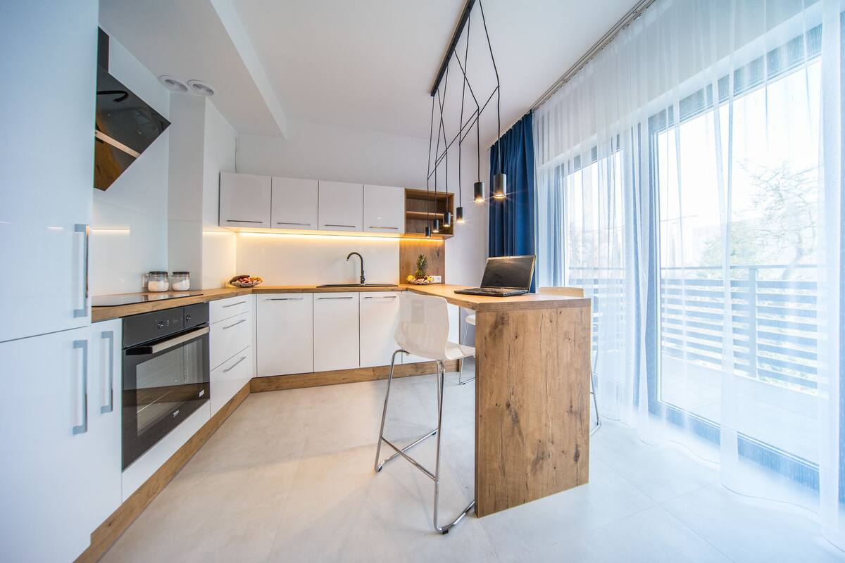 A modern kitchen with white cabinetry, a wooden countertop, and a bar area.