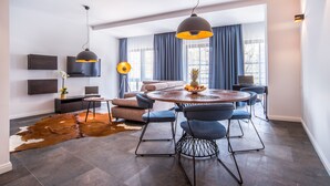 Un salon moderne avec une table de salle à manger ronde, des chaises bleues, un canapé et un tapis en peau de vache.
