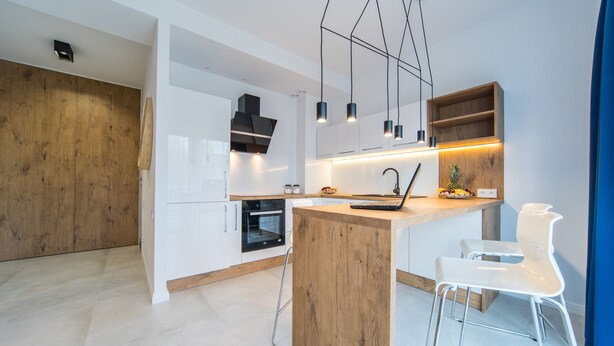 Une cuisine moderne avec des armoires blanches, un îlot central en bois et des luminaires suspendus.