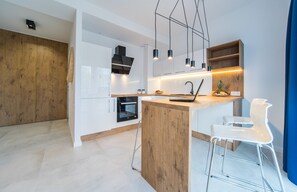 Una cocina moderna con armarios blancos, una isla de madera e iluminación colgante.