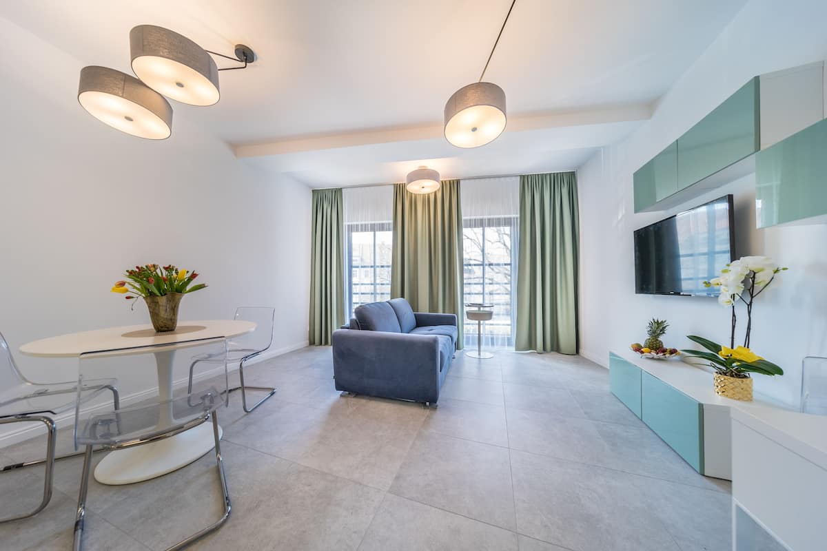 A modern living room with a sofa, a dining table with chairs, and a TV mounted on the wall.