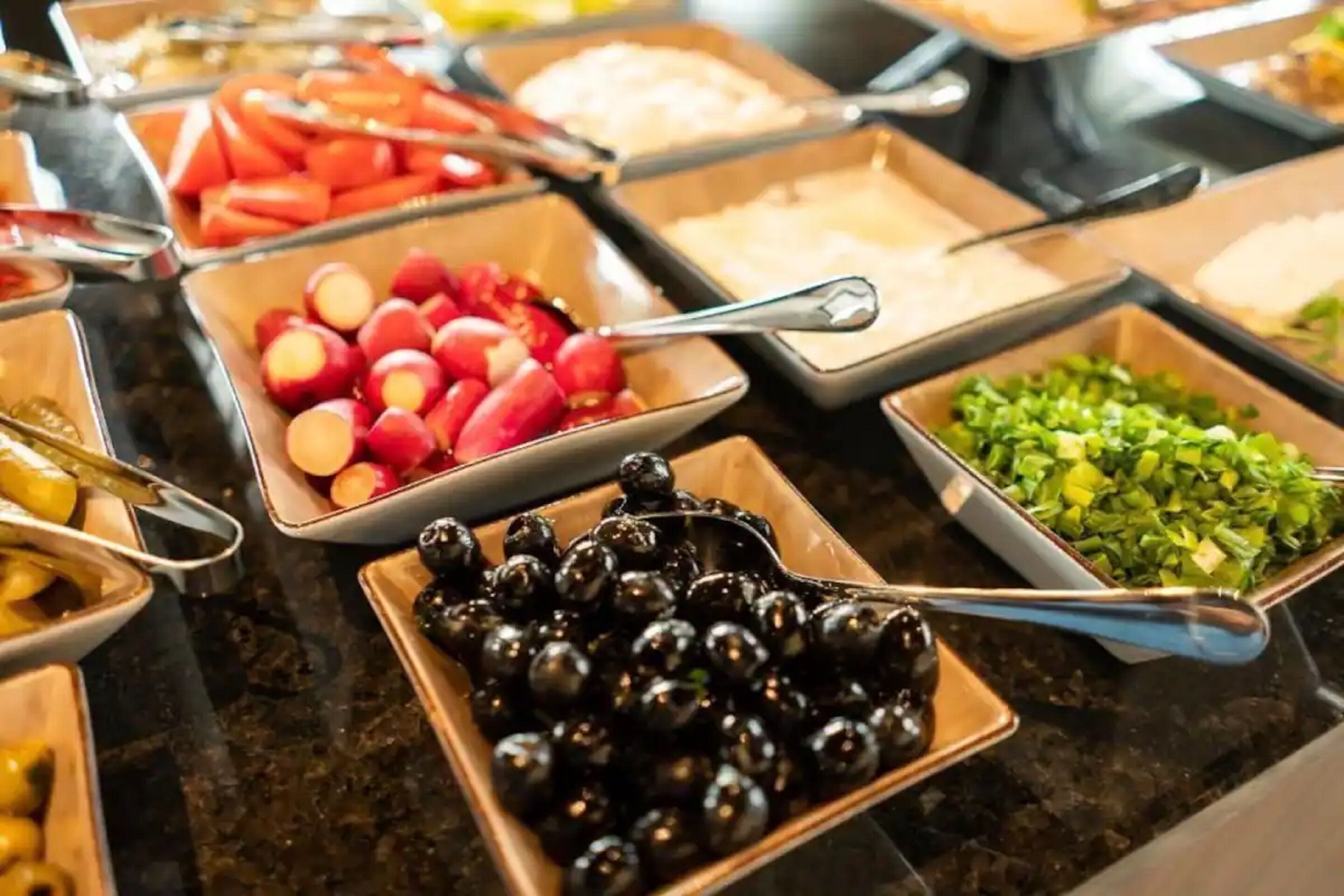 Un bufé con diferentes opciones de comida, incluyendo frutas, verduras y otros platos.