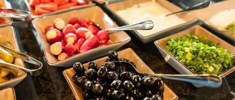 Un bufé con diferentes opciones de comida, incluyendo frutas, verduras y otros platos.