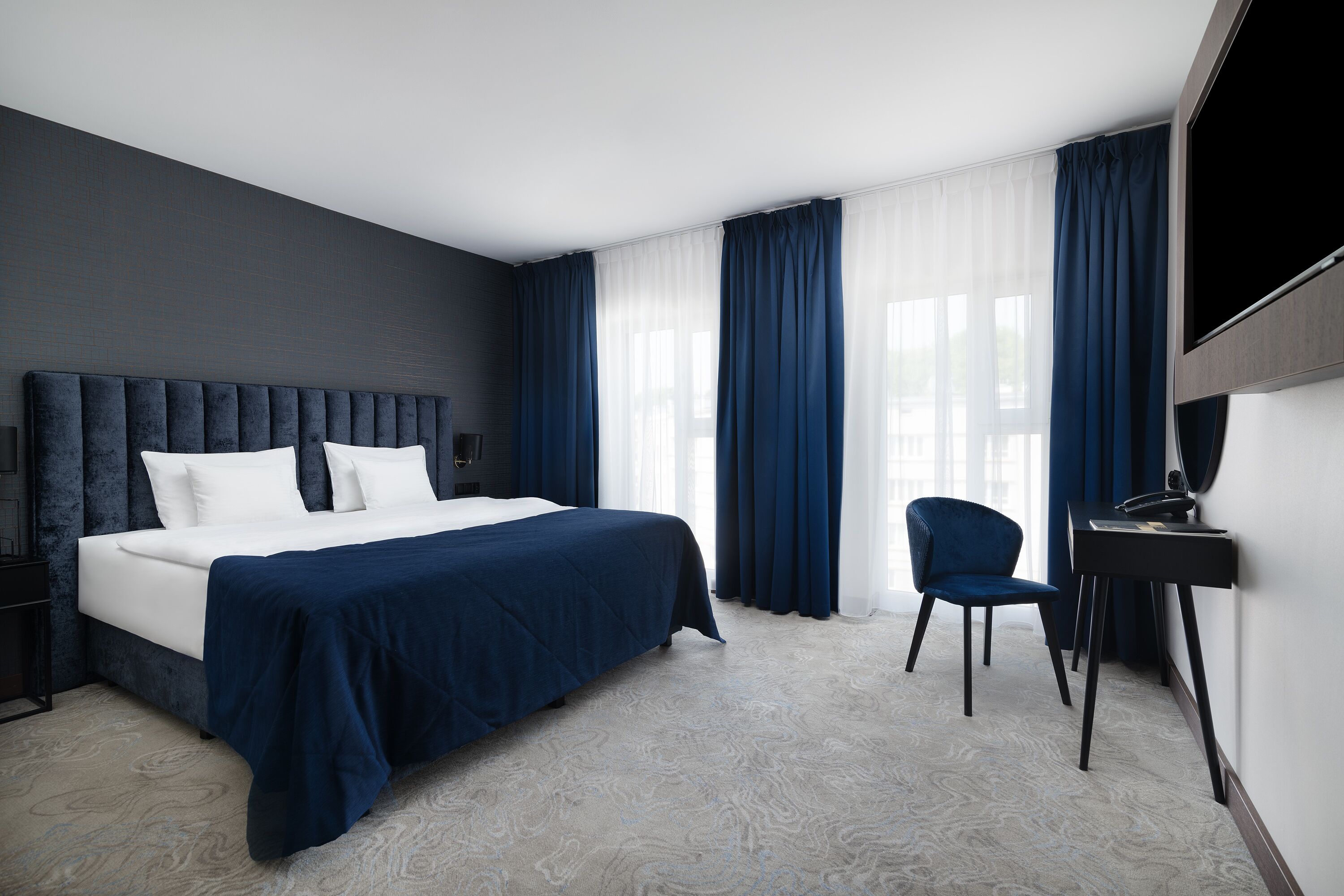 Una habitación de hotel moderna con una cama grande, un escritorio y una silla.