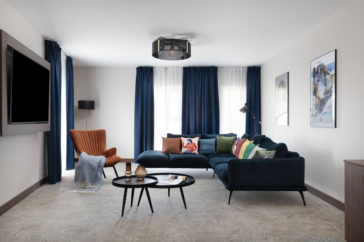 Un salon moderne comprenant un canapé, un fauteuil, une table basse et un téléviseur à écran plat.