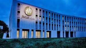 Un moderno edificio de hotel con un llamativo logotipo 'fh' y señalización que indica 'focus hotel'.