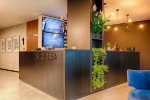 A reception desk with a digital screen, a blue chair, and a plant.