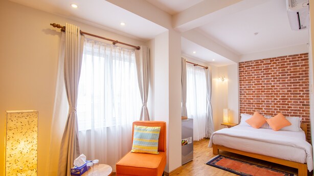 Una habitación de hotel con una cama, una silla, una mesa y una pared de ladrillo.