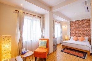 A hotel room with a bed, a chair, a table, and a brick wall. - Laxmi Niwas (Lalitpur)