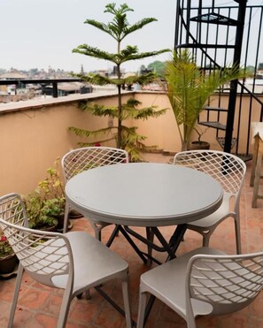 A round table with four chairs on a rooftop terrace. - Laxmi Niwas (Lalitpur)