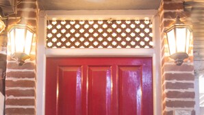 Una puerta roja con un aldabón de latón y una pequeña ventana encima.