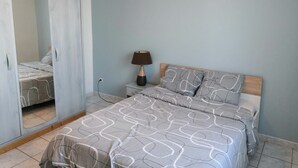 A bedroom with a bed, a bedside lamp, and an air conditioning unit on the wall.