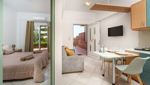 A modern hotel room with a bed, a sofa, a dining area with a table and chairs, and a TV mounted on the wall. - FnK Apartments (Malevizi)
