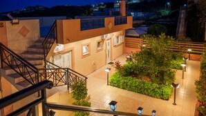 A multi-level building with a staircase, outdoor seating area, and well-lit pathways. - FnK Apartments (Malevizi)