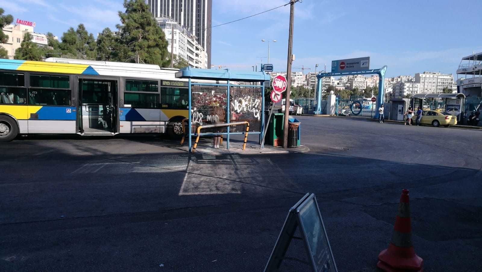 A bus stop with a shelter, a stop sign, and a pedestrian crossing.