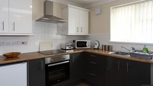Una cucina compatta con mobili bianchi, un forno a microonde, un tostapane e un lavello.