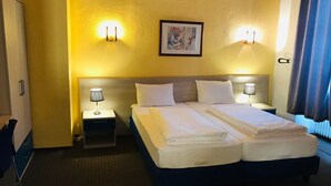 A hotel room with a double bed, two bedside tables with lamps, a small desk, and a chair. - Hotel restaurant germania (Bernkastel-Kues)