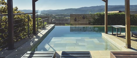 Una piscina al aire libre, sombrillas, sillones reclinables de piscina