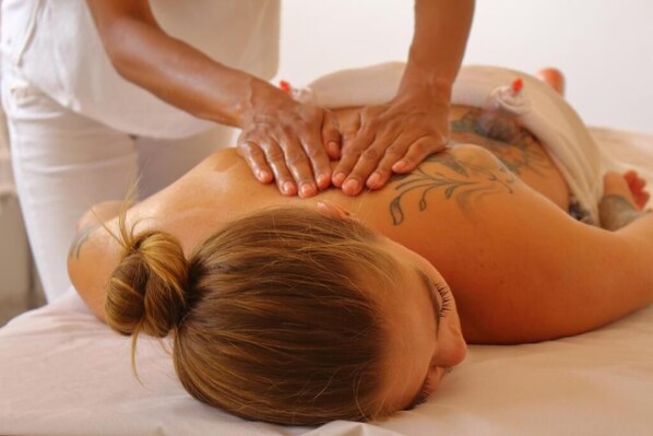 Een persoon ontvangt een rugmassage op een bed.