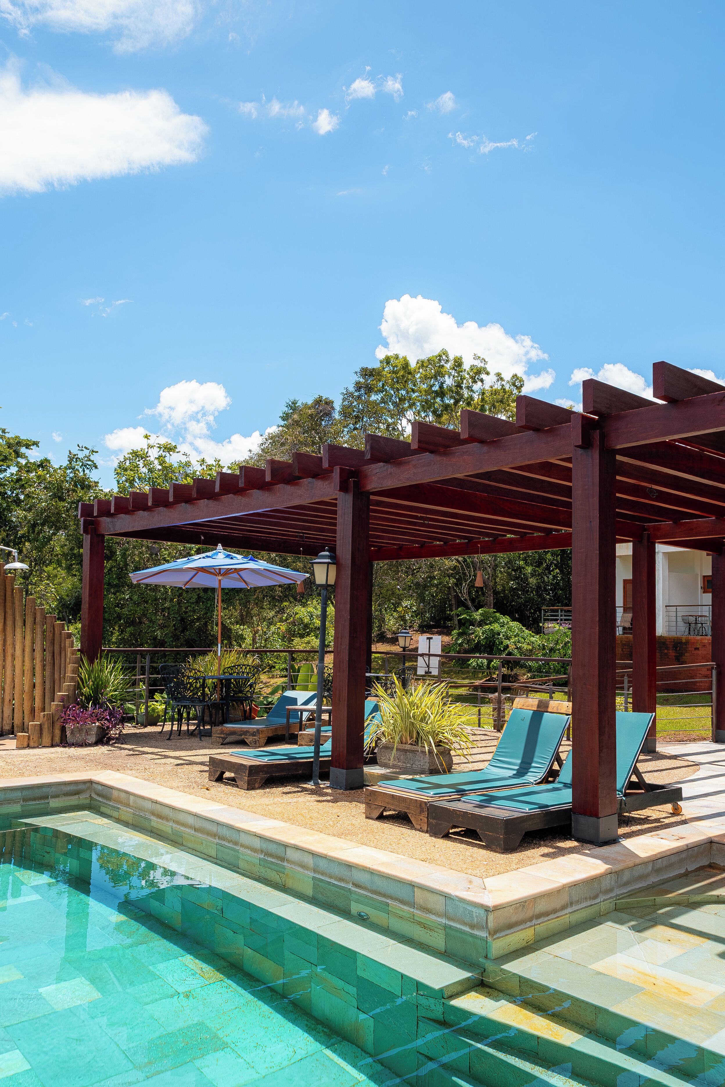 Una piscina al aire libre, sombrillas, sillones reclinables de piscina
