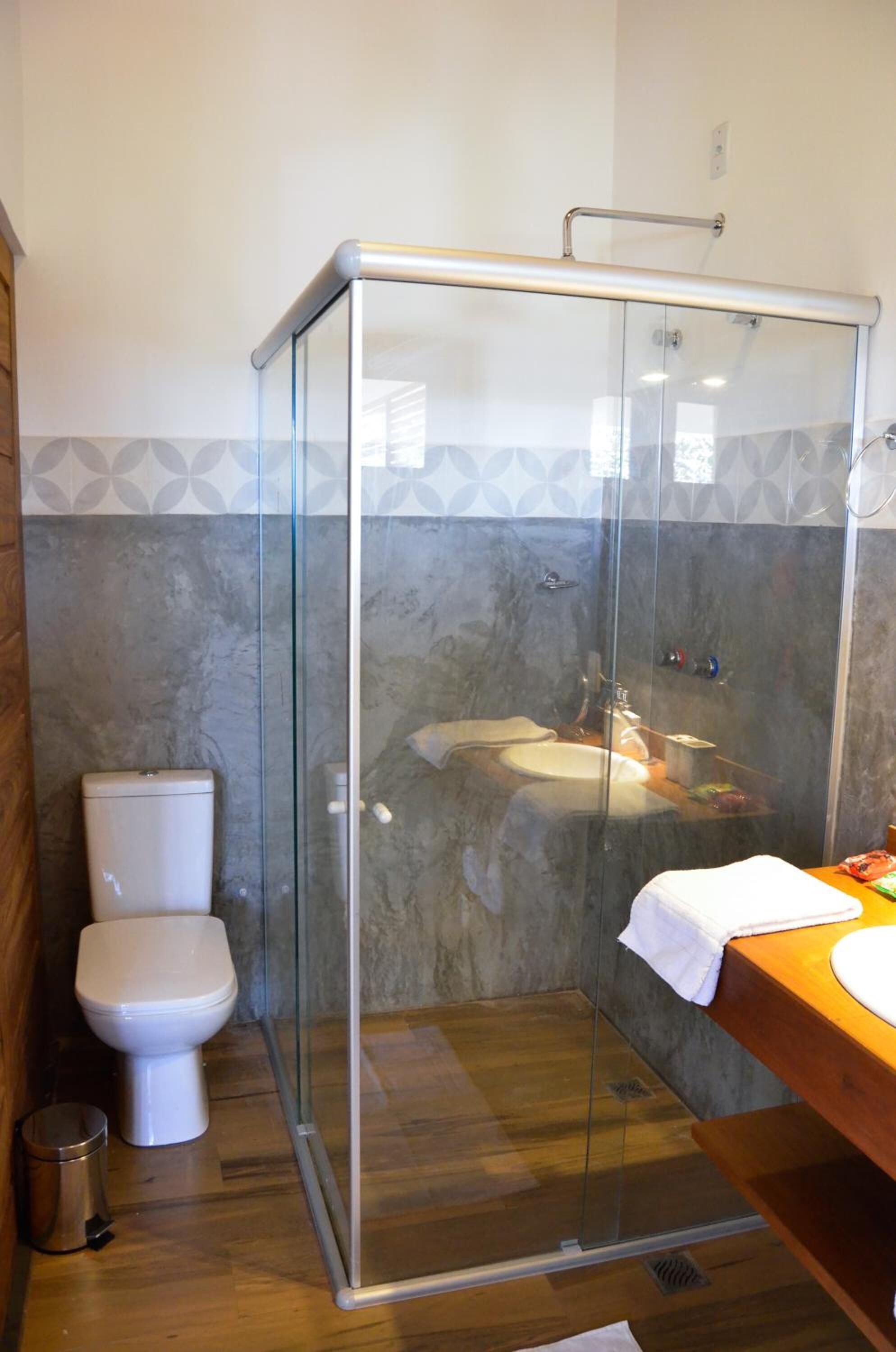 Ein Badezimmer mit Duschkabine, Toilette und Waschbecken mit Holzplatte.