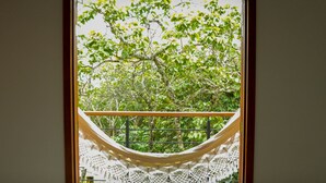 Una hamaca atada a la barandilla de un balcón, con vista a un árbol.