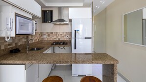 Una cocina moderna con microondas integrado, estufa a gas y refrigerador blanco.
