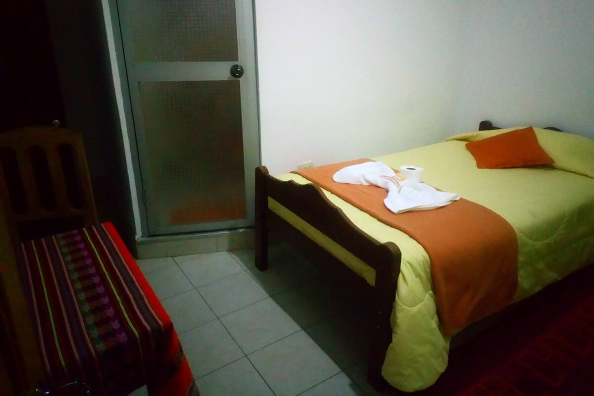 A small, simple room with a bed, a chair, and a door.