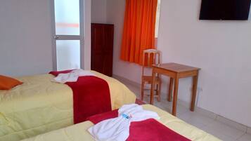 Habitación de hotel con dos camas, un escritorio y un televisor.