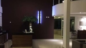 A modern lobby with a reception desk, a potted plant, and a large window.